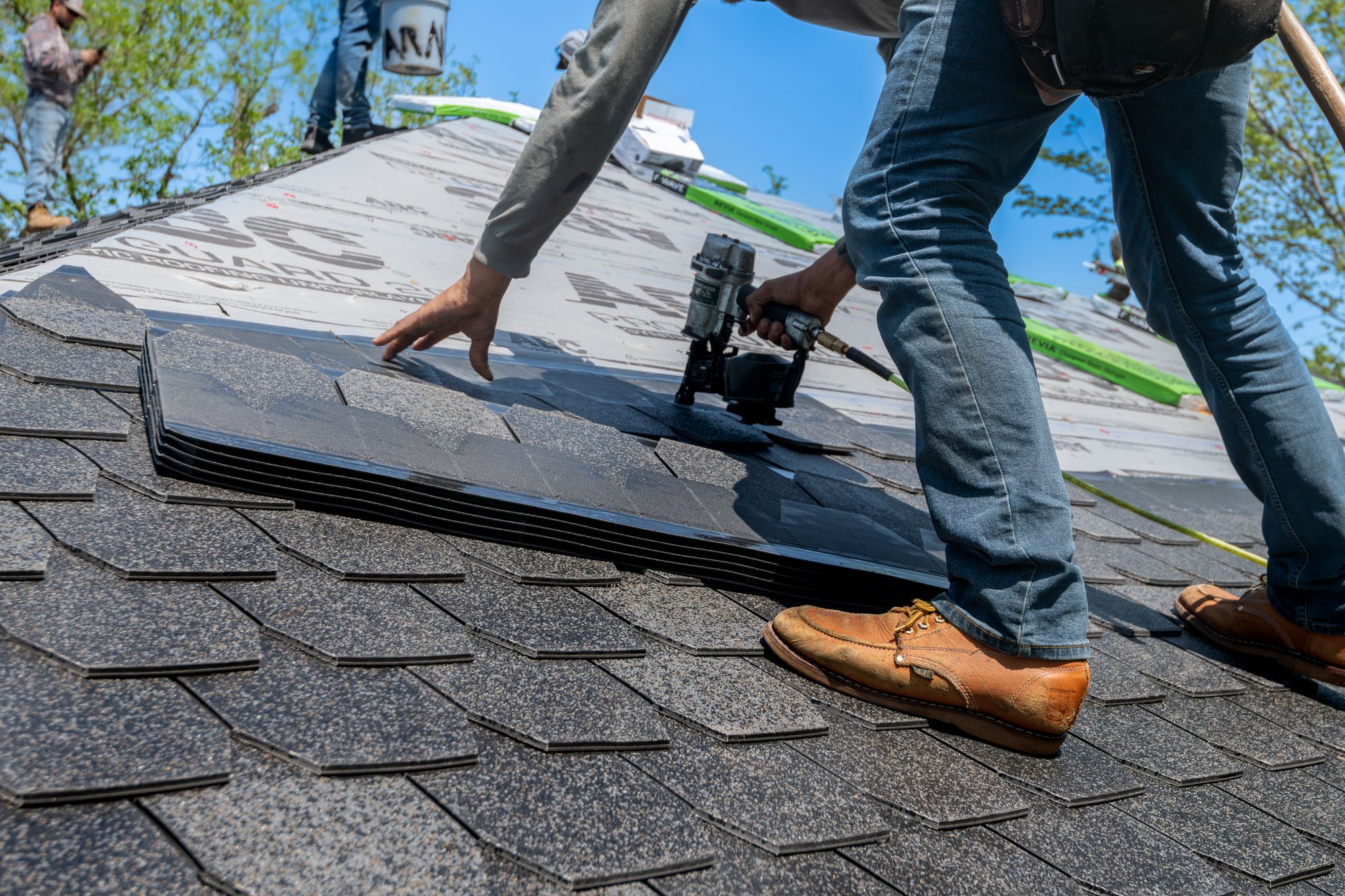 Roofing contractor installing shingles on a residential roof
